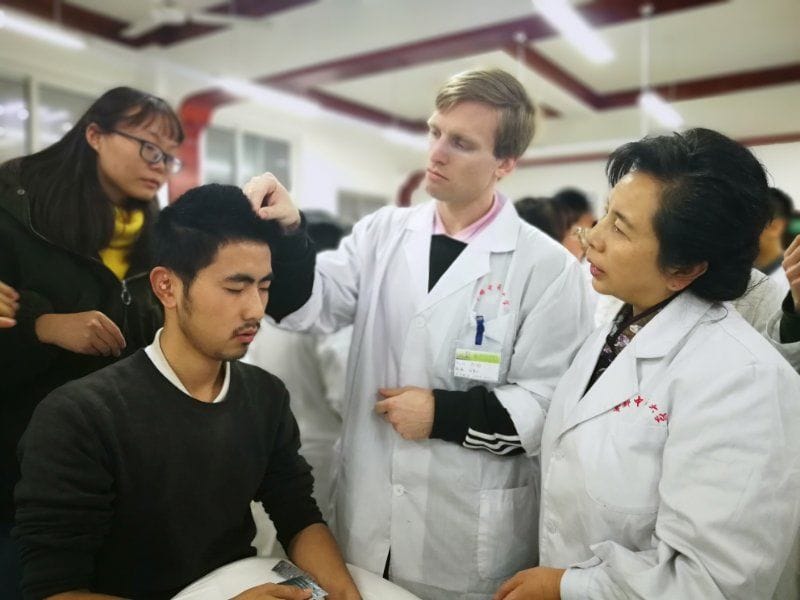 Acupuncture students observing patient assessment and treatment planning during hands-on training at CDUTCM